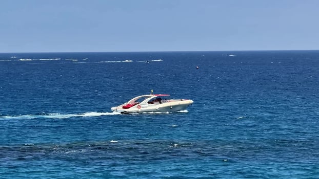 Experience the exhilarating thrill of speed as a sleek yacht navigates through vibrant blue ocean water photo