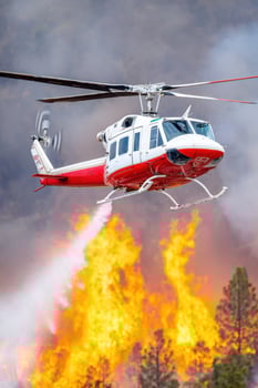 Helicopter dropping water over wildfire in forest photo