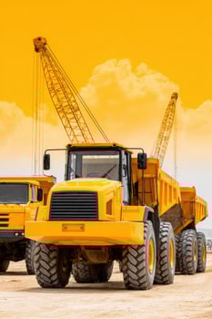 Heavy dump truck and cranes dominating construction site under yellow sky photo