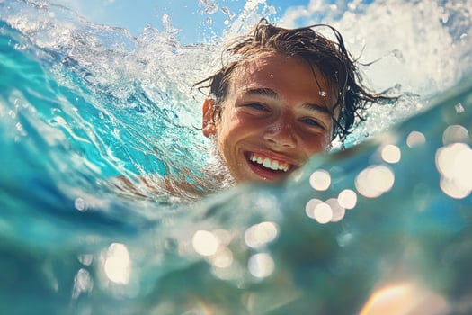 Smiling young boy emerges from a wave, enjoying refreshing water under bright sunlight photo