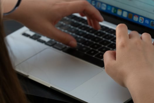 A person typing on a laptop computer photo