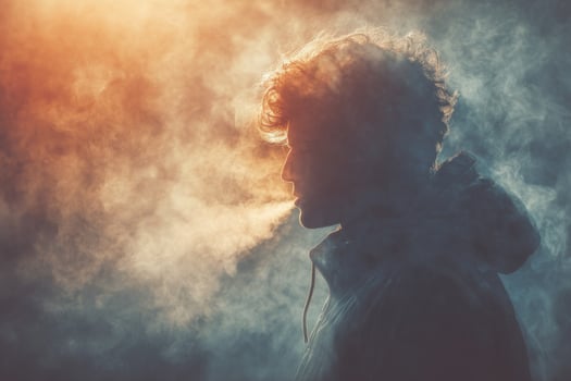 A man in a hoodie is smoking a cigarette photo