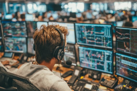 A man wearing headphones and sitting at a desk with multiple monitors photo