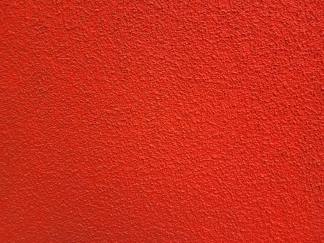 A bright background, a roughly plastered wall painted red. photo