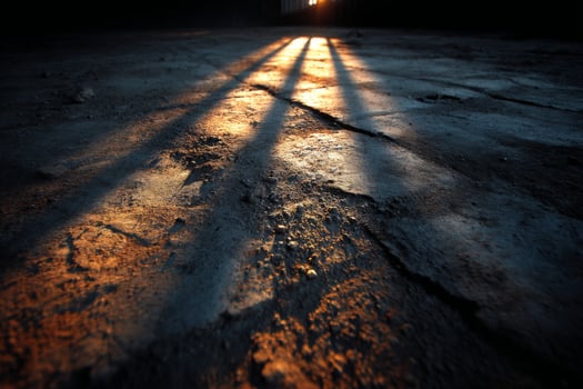 The sun shines through the shadows of a concrete floor photo