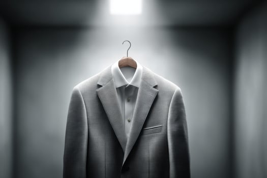 A suit hanging on a hanger in a dark room photo