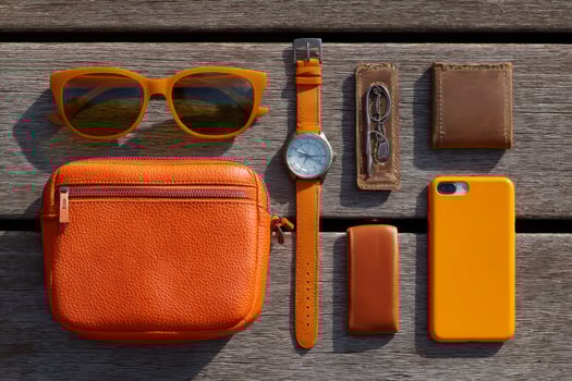 A wooden table with a watch, sunglasses, wallet, and phone photo