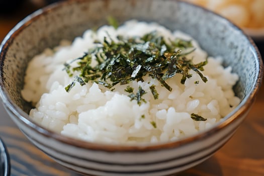 Steaming Bowl of White Rice with Seaweed Topping. photo