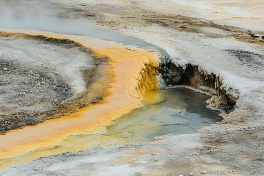Steaming geothermal landscape with colorful mineral deposits and bubbling water. photo