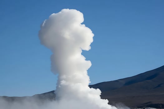 Powerful Geyser Erupting in a Volcanic Landscape Under Blue Sky. photo