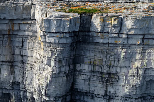 Striking Cliff Face Texture with Cracks and Green Moss Patches. photo