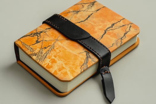 Artistic golden wheat notebook is secured with a handcrafted leather strap on a solid backdrop photo