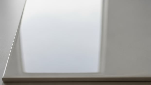 A white glass surface with a reflection of a window photo