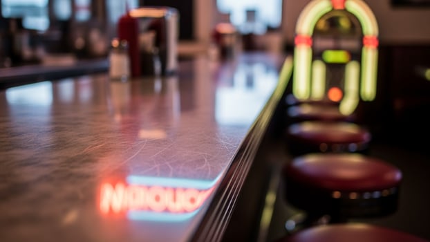 A bar counter with red stools and a jukebox photo
