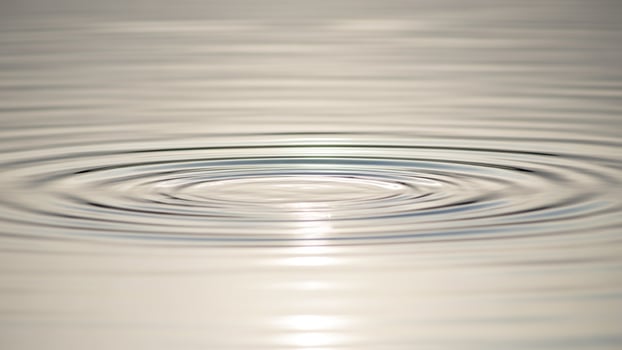 A circular ripple in the water with a sun shining photo