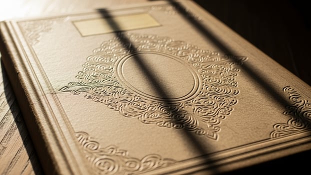An old book sitting on a table with the sun shining through the window photo