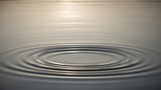 A circular ripple in the water with a sun in the background photo