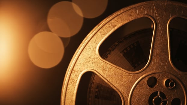 A film reel is shown in front of a bright light photo