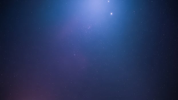 A blue and purple starry sky with a bright light photo