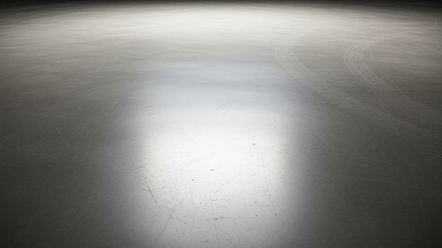 An empty ice rink with a light shining on it photo