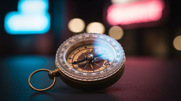 A compass is sitting on a table in front of a neon sign photo