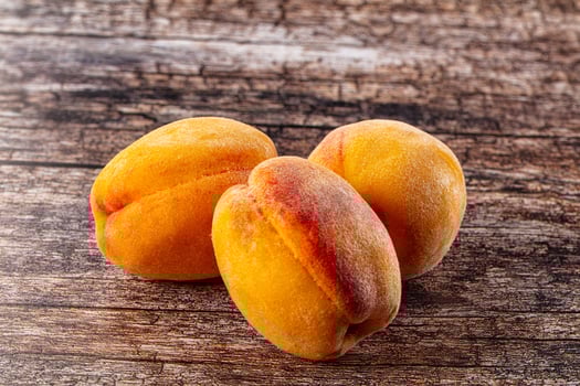 Three ripe apricots on a wooden table photo