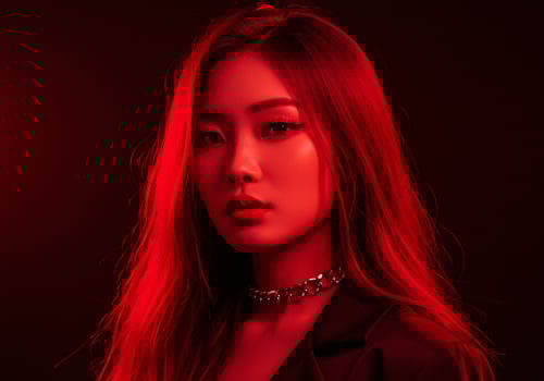 Confident asian woman posing in a studio, using red light to accentuate beauty photo