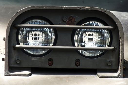 The headlights of a car are lit up, illuminating the area around it. The headlights are positioned on the front of the car, providing a clear view of the road ahead. The bright light casts a warm glow photo