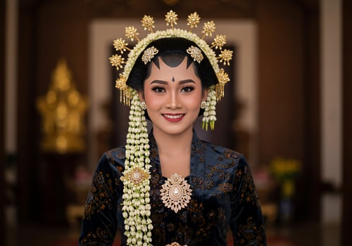 Javanese woman in traditional dress poses smiling indoors at cultural ceremony photo