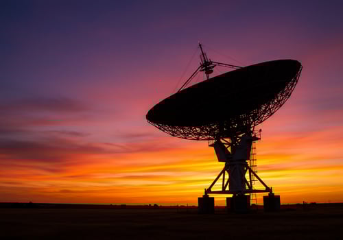 An antenna sits in the middle of a field at sunset photo