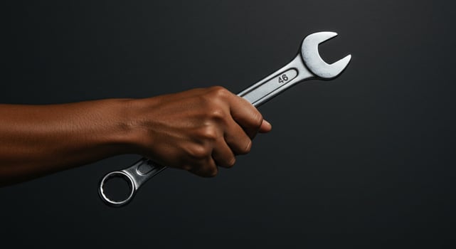 Mechanic's dark hand holding wrench tool, equipment, repair service. Isolated shot photo