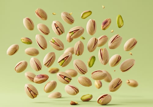 Pistachios levitate on light green backdrop, suggesting snack, food, or health ads photo