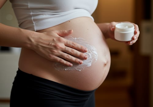 Pregnant woman applies lotion to her growing belly in a home bathroom setting photo