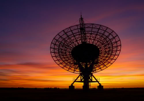 Radio Telescope in silhouette against dramatic sunset sky. Space exploration photo
