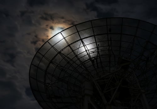 The moon is seen through the satellite dish photo