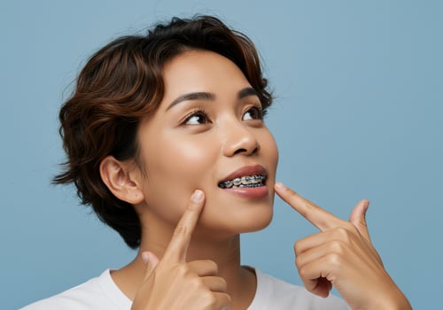 Smiling woman shows off braces, dental care. Background studio with blue wall photo