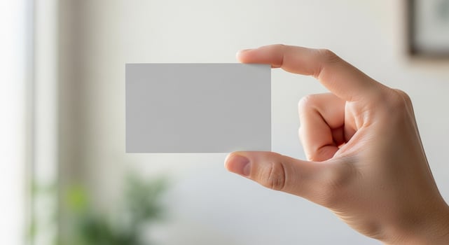 A person holding a blank card in front of a window photo