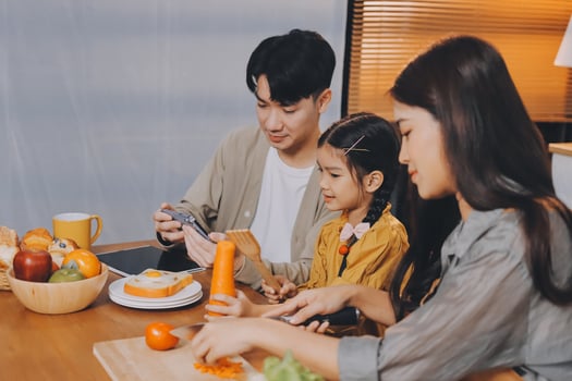 Asian family eating vegetables and fruits while using a smartphone photo