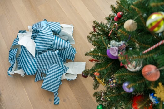Christmas gift wrap waste on floor highlighting excessive paper use after holiday unwrapping photo