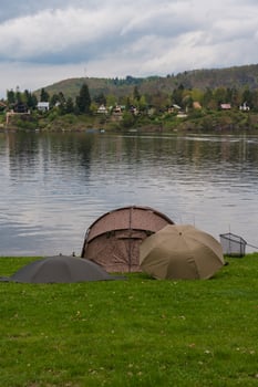 Fishing tents and rods on riverbank at Nova Zivohost, vertical slide photo