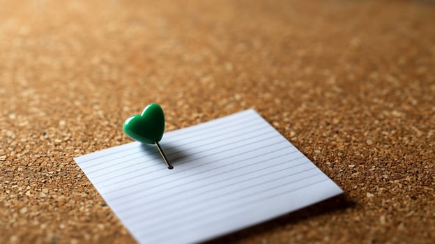 Heart-Shaped Push Pin on a Note Pad on Corkboard photo