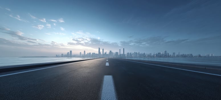 The serene road leading towards a stunning urban skyline over calm waters photo