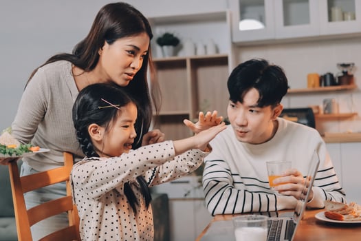 A family is sitting at a table with a child reaching for something photo