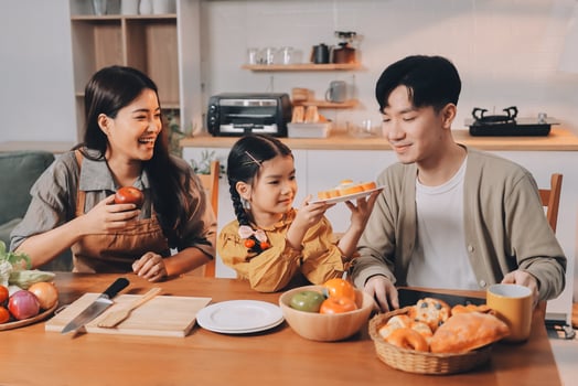 Asian family eating pizza and fruits together at the kitchen table photo