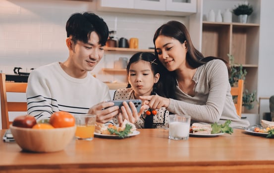 Asian family using smartphone while eating breakfast photo
