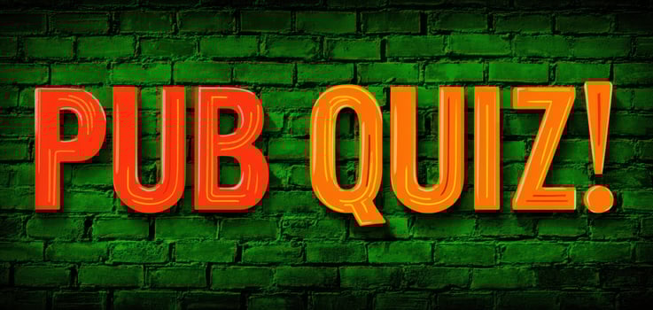 The vibrant neon sign announcing a fun pub quiz event on a brick wall photo
