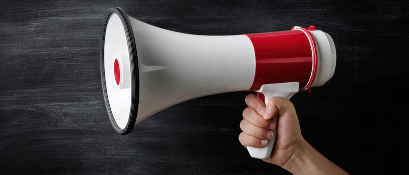 The megaphone held in hand against a dark chalkboard background. photo
