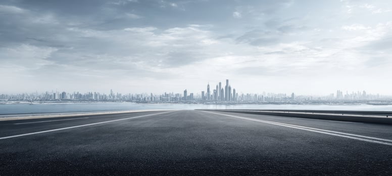 The expansive road leading towards a modern city skyline under a cloudy sky photo