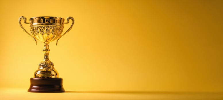 The golden trophy shining against a vibrant yellow background. photo