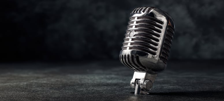 The vintage microphone standing elegantly on a dark textured surface. photo